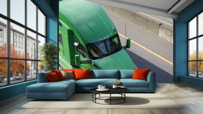 Green big rig semi truck for long haul cargo transporting dry van semi trailer on the road Wall mural