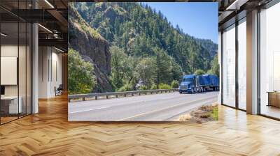 Powerful blue big rig semi truck transporting heavy duty cargo covered with tarp on flat bed semi trailer driving on the highway road in Columbia Gorge Wall mural