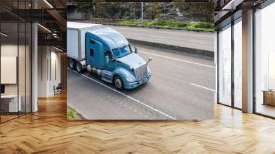 Powerful blue gray big rig semi truck transporting cargo in dry van semi trailer driving on the divided lower highway road Wall mural