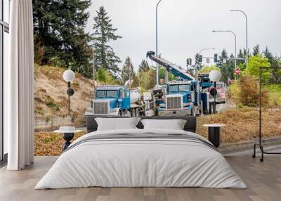 Powerful towing semi truck with arrow using help of other semi trucks trying to lift top truck trailer that overturned while driving at the entrance to the highway Wall mural