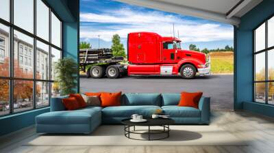 Profile of the American bonnet red big rig semi truck with extended cab and loaded by pipes flat bad semi trailer standing on the industrial parking space waiting for delivery freight Wall mural