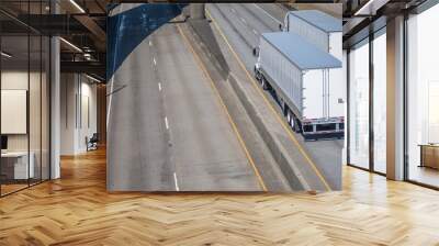 Two big rigs semi trucks with semi trailers running on opposite lanes in opposite directions Wall mural