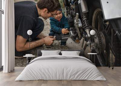 A father on the street shows his young son how to fix a motorcycle. Father-son communication. Wall mural