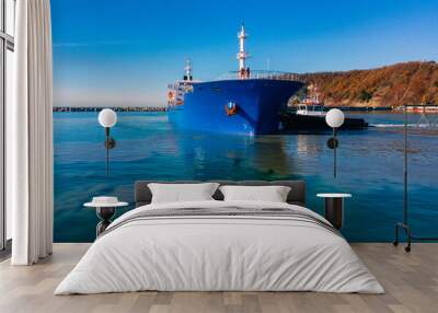 Two tugboats work in tandem to turn the ship out of the harbor at the seaport. Wall mural