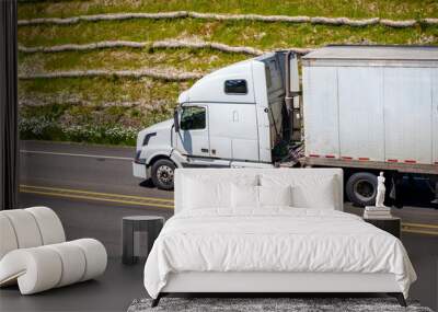 White big rig semi truck with dry van semi trailer driving on the road with hill on the background Wall mural