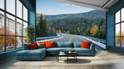 Winding highway between wooded mountains with evergreen and deciduous trees sprinkled with the first snow on a pass in Vermont Wall mural