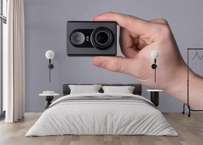 hand holding black action camera on grey background Wall mural