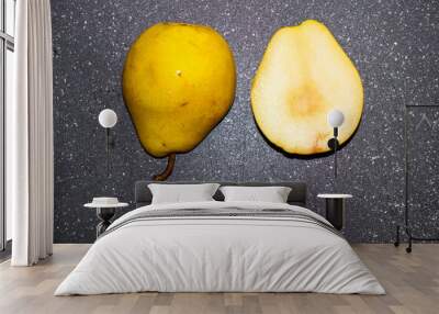 Yellow ripe pear cut in half on black chopping board. Autumn still life Wall mural