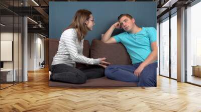 A young woman shouts at a young man. A man does not pay attention to a woman. Sitting on the couch Wall mural