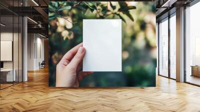 A white template card in a hand on an outdoor background Wall mural