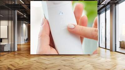 Close up of white ultrasonic skin scrubber in female hand. Finger pointing on the word 