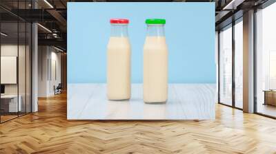 Two bottles of milk with red and green cap on blue background. Wall mural