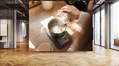 Measuring flour with electronic kitchen scales for cooking something. Girl pouring flour to the metal cup for precise measuring Wall mural