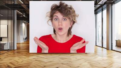 Close- up portrait of a young rather surprised woman with an open mouth standing with open hands, isolated on a grey background Wall mural