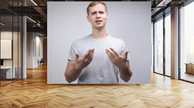 Studio portrait concept of a smiling young man talking on a white background. He stands directly in front of the camera in different poses with different emotions. Wall mural