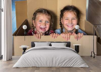 Smiling children look out of cardboard box. Moving concept. Wall mural