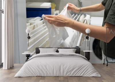 A girl hangs clean laundry on a drying rack Wall mural