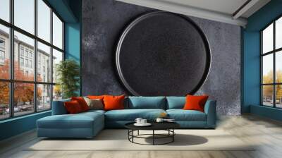 Empty round black plate on dark moody dark background with copy space. Overhead view Wall mural