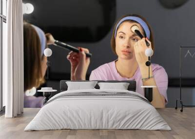 Fashionable beautiful woman standing in front of the mirror in lavatory at the night time. Attractive girl preparing for dating and party Wall mural