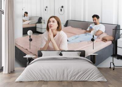 Frustrated and depressed woman sitting on the edge of the bed after conflict with her husband because of his erectile dysfunction problem Wall mural