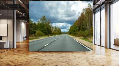 autumn road in the forest with dramatic clouds  Wall mural