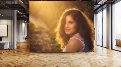 Outdoor portrait of beautiful young woman with  long curly hair Wall mural