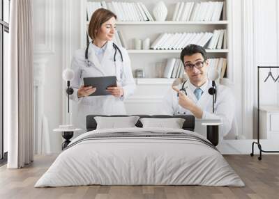 Portrait photo of two young smiling doctors in white medical gown in the clinic office. Colleagues meeting, discussion and health care concept Wall mural