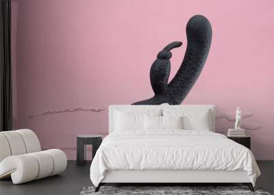 Black vaginal vibrator in drops of water hanging in the air on a pink background Wall mural