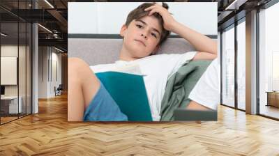 Tired school boy reading book in the bedroom Wall mural