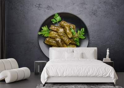 Top view delicious stuffed grape leaves dolma with parsley in black plate on dark wood background. Copy space Wall mural