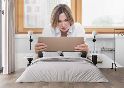 Young attractive woman sitting at the table and working on laptop in the kitchen at home	 Wall mural