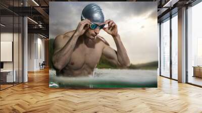 Sport backgrounds. Young athletic swimmer standing near the sunset river.  Wall mural