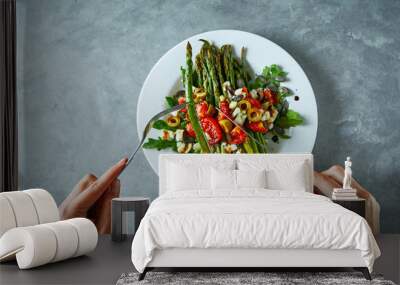 First person view on a dish with roasted asparagus, tomatoes, olives, cheese and arugula. Wall mural