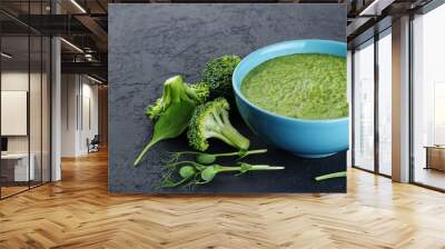 Bowl of green cream soup with pea sprouts, broccoli, kale and spinach on a dark background. Wall mural