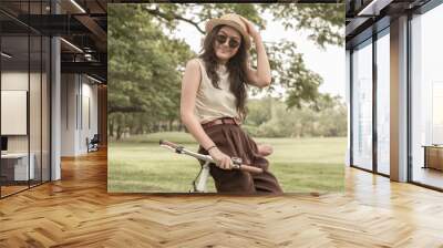 Woman chilling in the park with her bicycle Wall mural