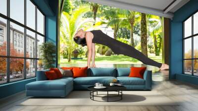 Young woman is practicing yoga and pilates on nature. Wall mural