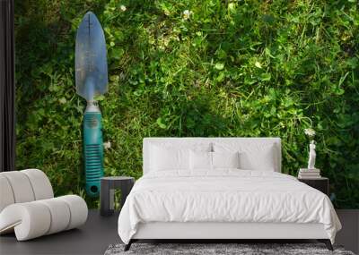 gardening tool leaning on a green meadow Wall mural