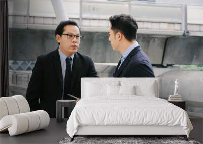 two business asian smart man in suit talking and reading information about finance news in mobile tablet together standing in modern city, network technology, internet, successful, teamwork concept Wall mural