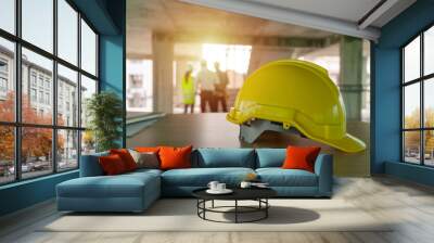 yellow safety helmet on workplace desk with construction worker team engineer or inspector checking new project contract at construction site background, engineering, construction, contractor concept Wall mural