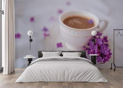 Cup of coffee with lilac flowers on a white background. Wall mural