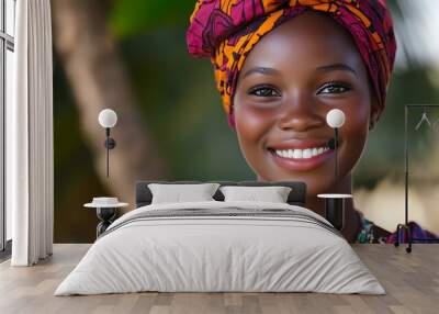 A beautiful Gambian woman. The-Gambia. A beautiful Gambian woman. A cheerful young woman wearing a vibrant African headwrap smiles warmly against a blurred natural background, showcasing joy an. #wotw Wall mural