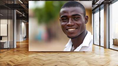 A handsome Togolese man. Togo. A cheerful young man smiles warmly at the camera, set against a blurred outdoor background, conveying positivity and approachability. . #motw Wall mural