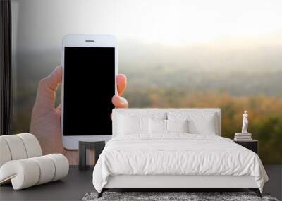 Hand holding mockup smartphone with sunlight and mountain backgr Wall mural