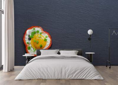 Fried eggs with red sweet pepper and chives on a black slate background. Top view. Wall mural