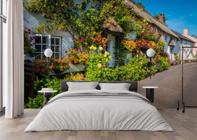 Cute old English house with a thatched roof and flowers in a green hilly landscape on a summer sunny day with blue sky in the UK in a holiday Dorset countryside between Sidmouth and Lyme Regis. Wall mural