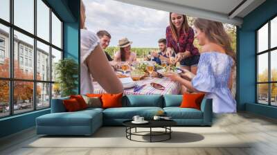 young adult friends have a picnic party outdoor beside a vineyard. they enjoy rose wine, seasonal simple food. Wall mural