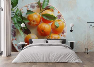 A decorative plate of ripe oranges with fresh green leaves, artistically arranged on a rustic surface, showcasing natural beauty and simplicity. Wall mural