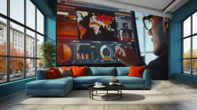 A man engrossed in studying various data points on a large monitor depicting urban analytics and world maps in a softly lit room. Wall mural