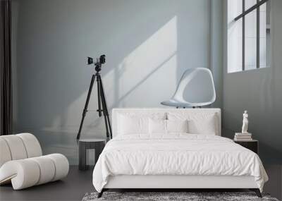 A minimalist studio with a white chair and a camera on a tripod, illuminated by natural light streaming through a large window. Wall mural