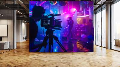 Backstage of a colorful concert, with a cameraman filming a performer on stage amidst vibrant lights and equipment. Wall mural